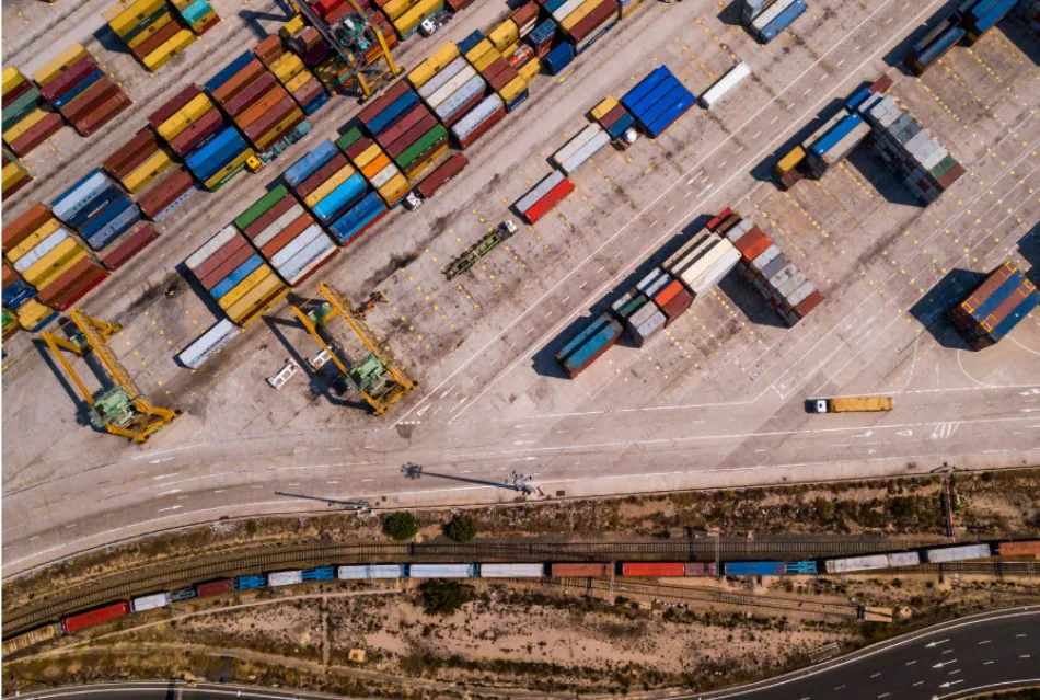 Aerial view of a busy shipping yard with colorful containers and logistics vehicles for freight transportation.